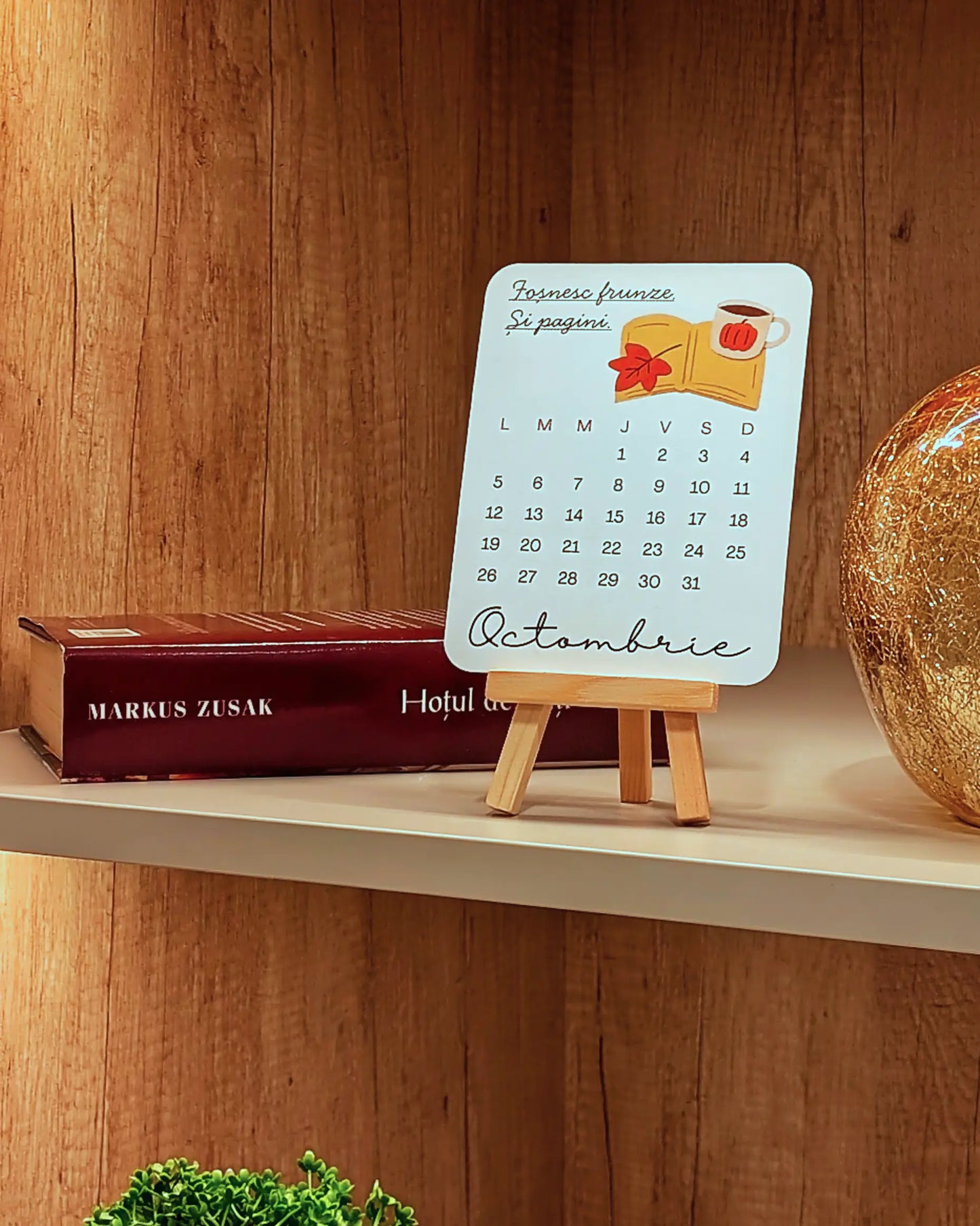 Small calendar on a wooden shelf with a book in the background